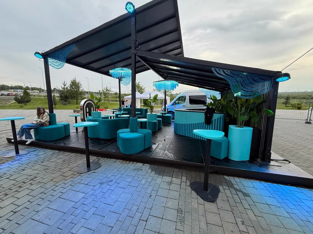 Zonă lounge de brand în aer liber, cu mobilier turcoaz și iluminare
